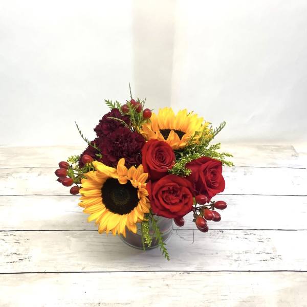 Bouquet of red roses and yellow sunflowers in a glass vase