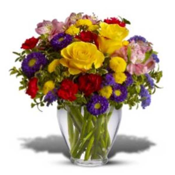 Mixed bouquet of yellow, red, purple, and pink flowers in a clear glass vase