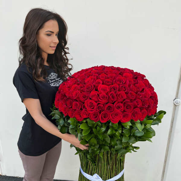 Woman holding a large bouquet of red roses with a green base