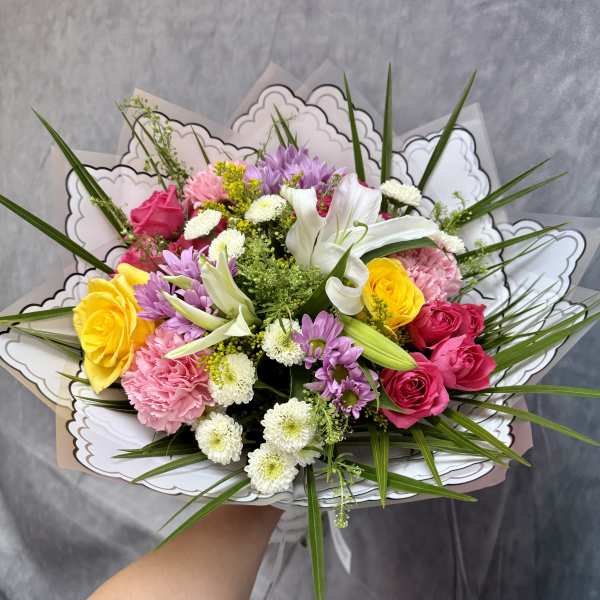 Mixed bouquet of roses, lilies, and daisies in decorative wrap