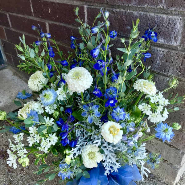 Blue and white mixed flower arrangement with ribbon at the base