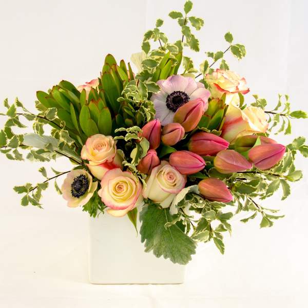 Bouquet of pink tulips and pale roses in a white vase