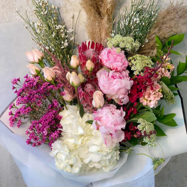 Mixed bouquet with pink peonies, white hydrangea, and red protea