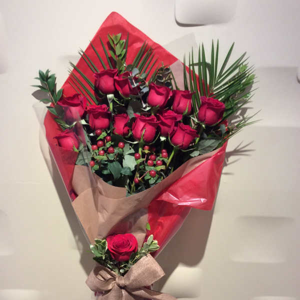 Bouquet of red roses wrapped in red and tan paper with a ribbon
