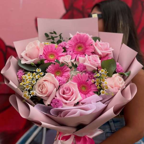 Pink bouquet of roses and gerbera daisies wrapped in pastel paper