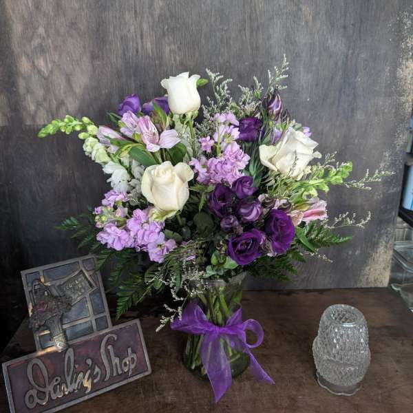 Purple and white bouquet in a glass vase with a ribbon