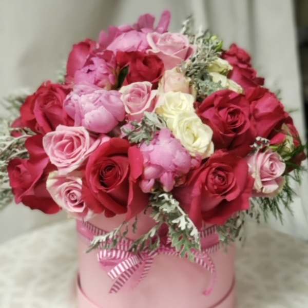 Pink and red roses arranged in a round pink box with a ribbon