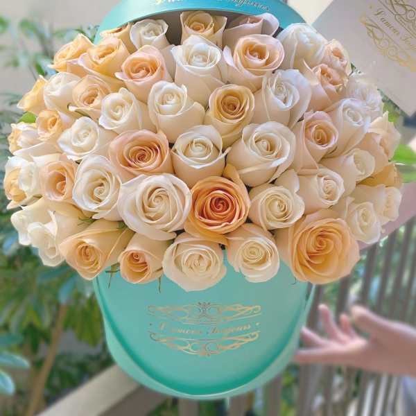 Bouquet of cream and peach roses in a turquoise hat box