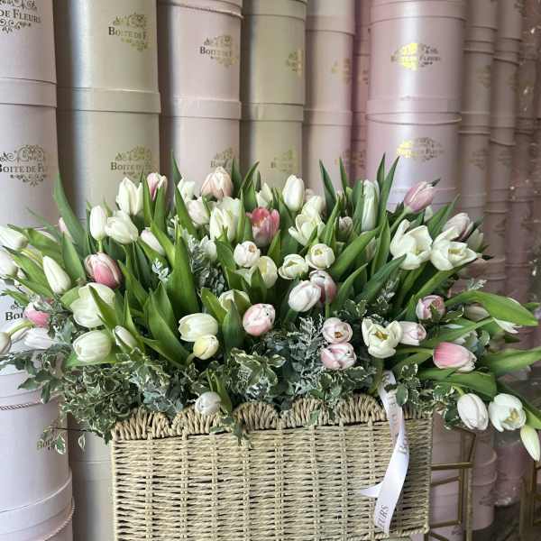 Basket arrangement of white and pink tulips with greenery