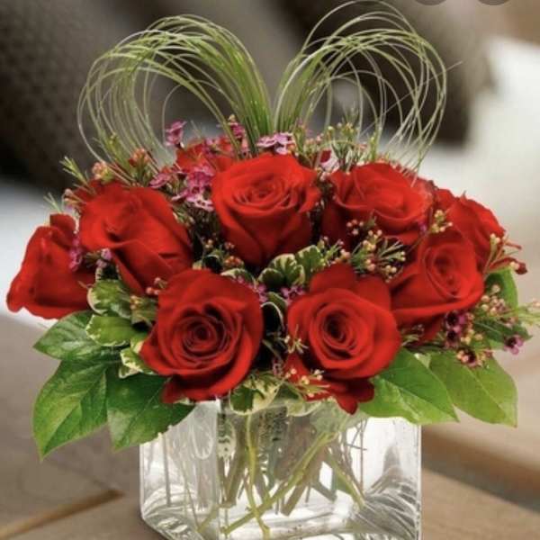 Red roses arranged in a clear square glass vase