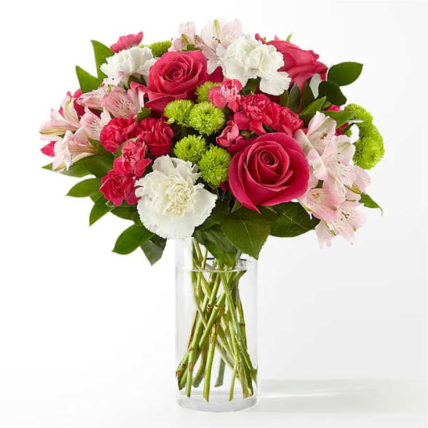 Bouquet of pink roses, carnations, and white flowers in a clear glass vase