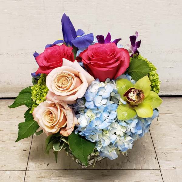 Bouquet of roses, hydrangeas, and orchids in a low square vase
