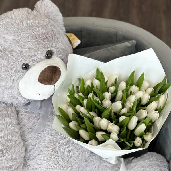 White tulip bouquet beside a large gray teddy bear