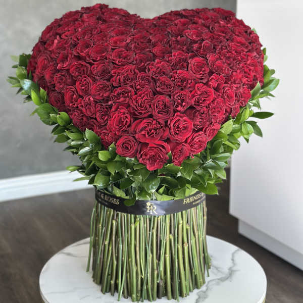 Heart-shaped bouquet of red roses with green foliage