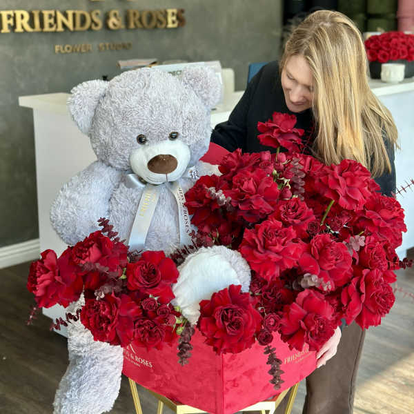 Large red rose arrangement with a gray teddy bear in a pink box