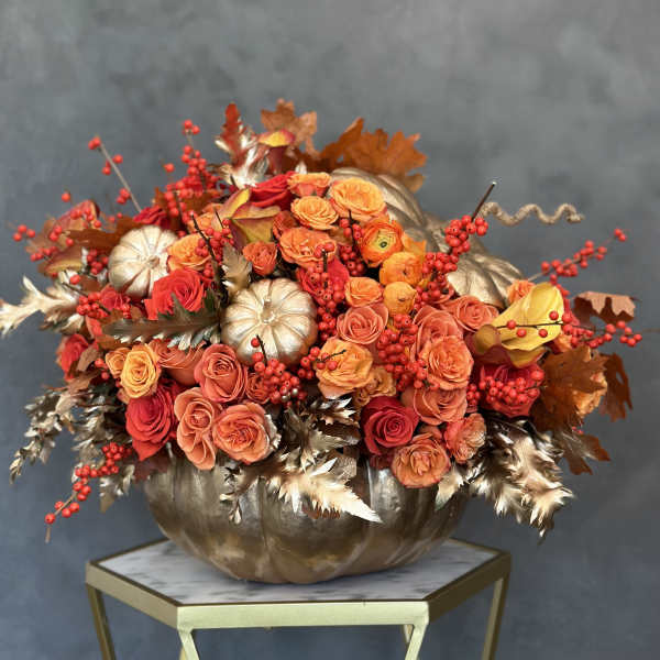 Orange and red rose arrangement in a metallic pumpkin container