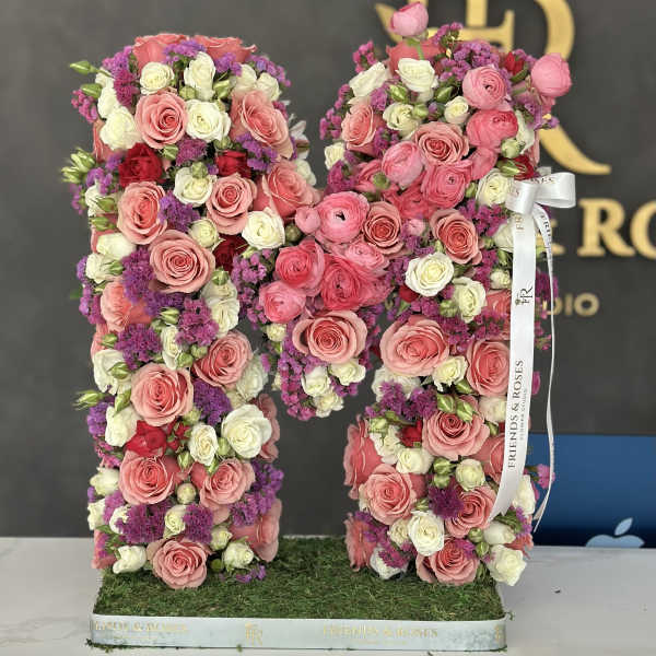 Large floral letter M covered in pink, white, and purple roses
