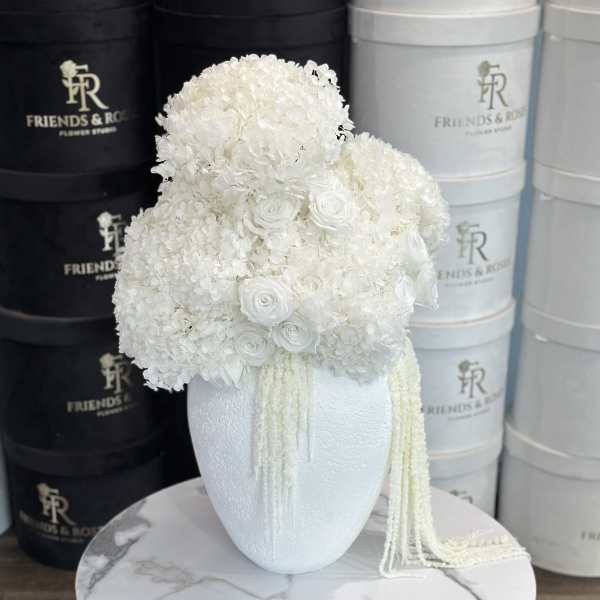 White floral arrangement in a textured vase with trailing strands