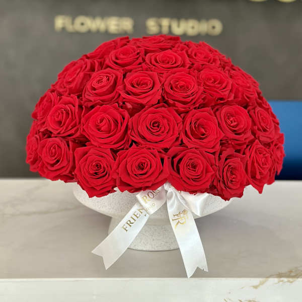 Round bouquet of red roses in a white hat box with ribbon