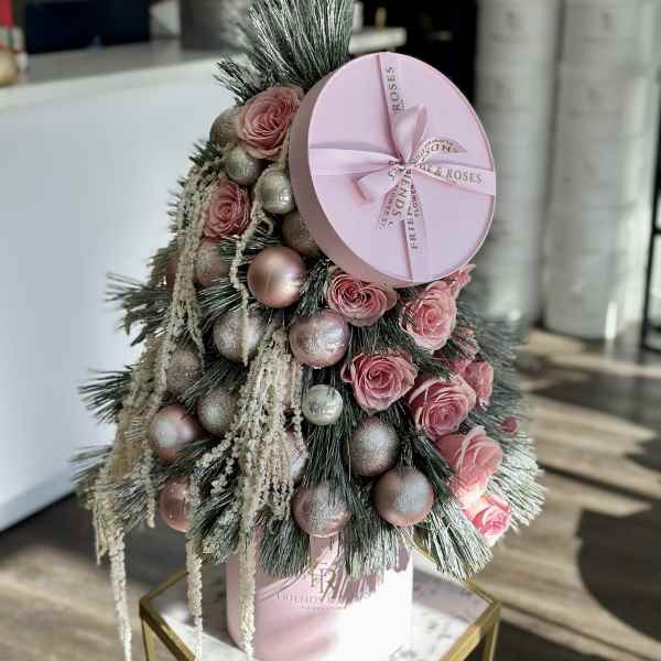 Pink roses arranged with ornaments in a pink hat box