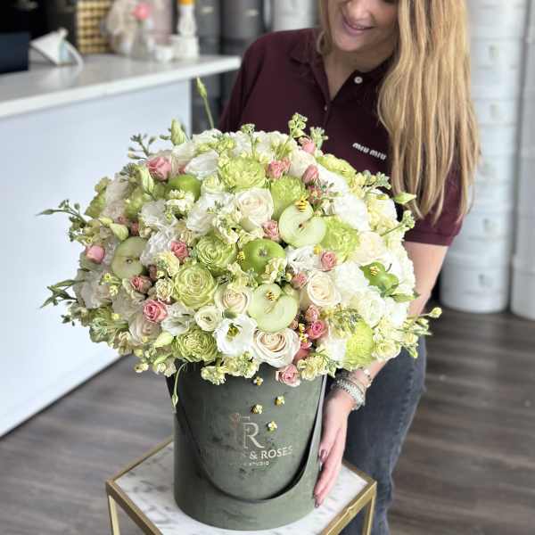 Large bouquet of white and pale green flowers in a green hatbox