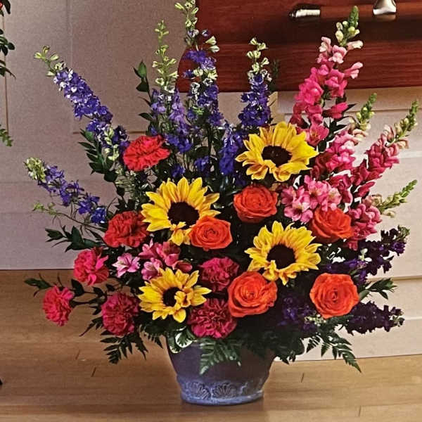 Colorful bouquet with sunflowers, roses, and tall purple spikes in a vase