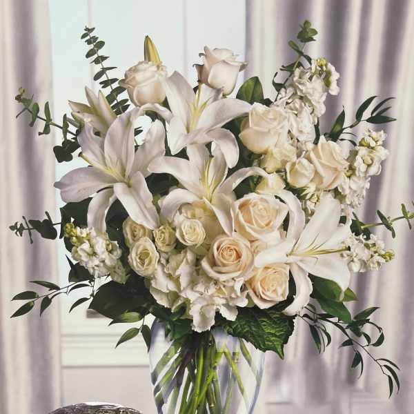 White lilies and cream roses in a clear glass vase