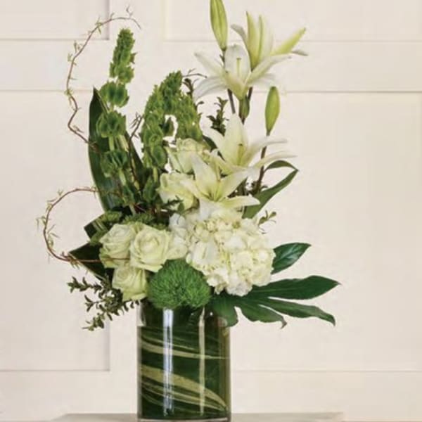 White lilies and pale roses in a tall glass vase