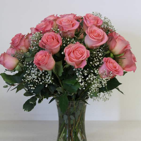 Pink roses arranged in a clear glass vase with baby's breath