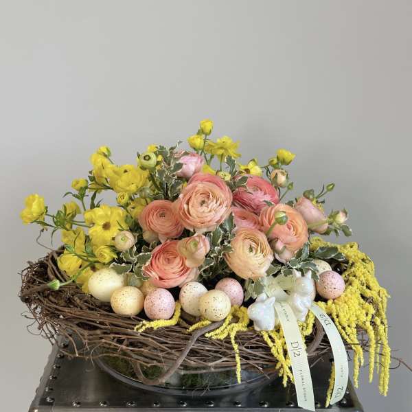 Pastel flower arrangement in a twig nest with decorative eggs and ribbon bows