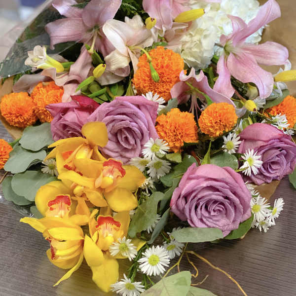 Bouquet of pink lilies, purple roses, and orange marigolds