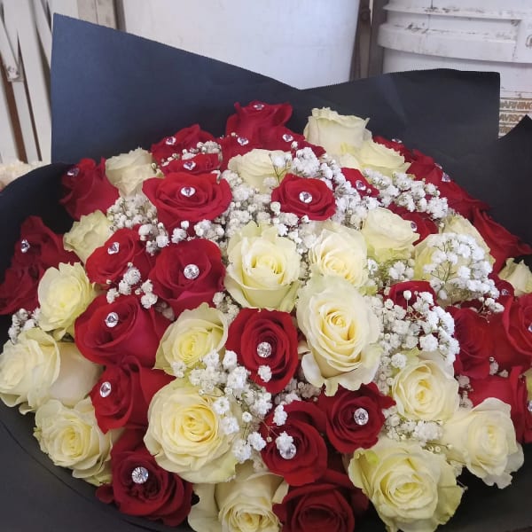 Bouquet of red and white roses with baby's breath in black wrap