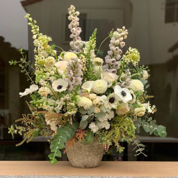 Tall white floral arrangement in a textured vase