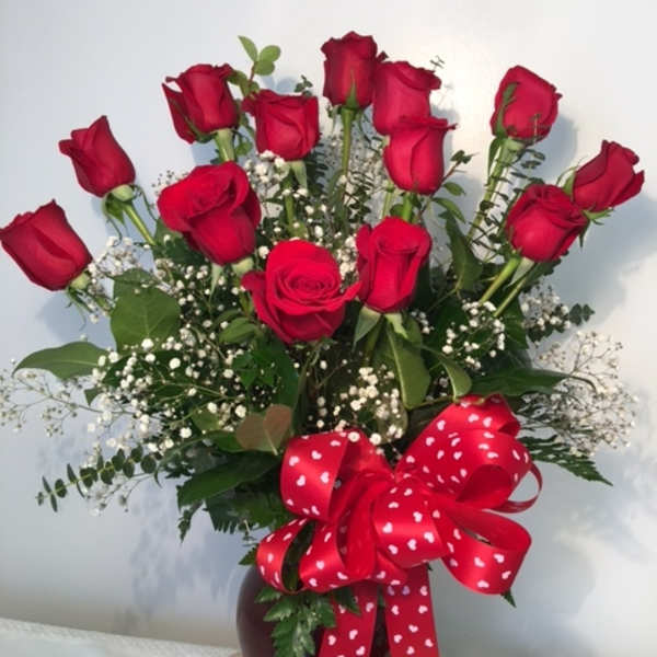Bouquet of red roses in a vase with a heart-patterned ribbon