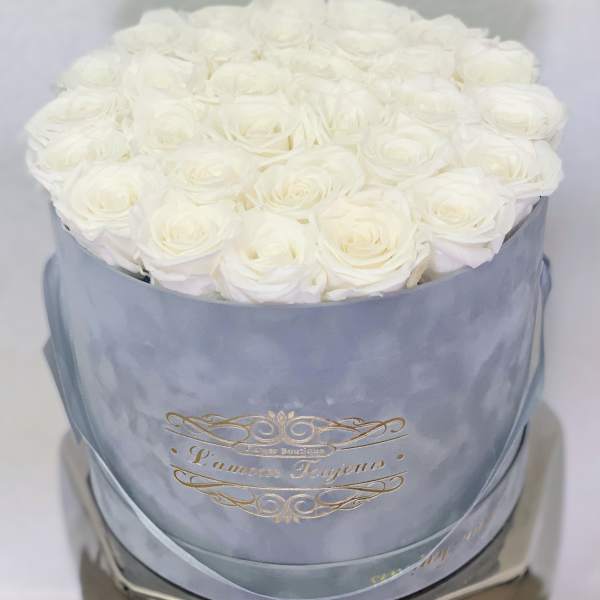 Round box filled with tightly packed white roses in a light blue container