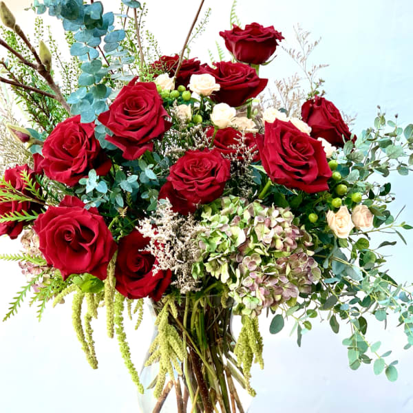 Bouquet of red roses, cream spray roses, and hydrangea in a glass vase