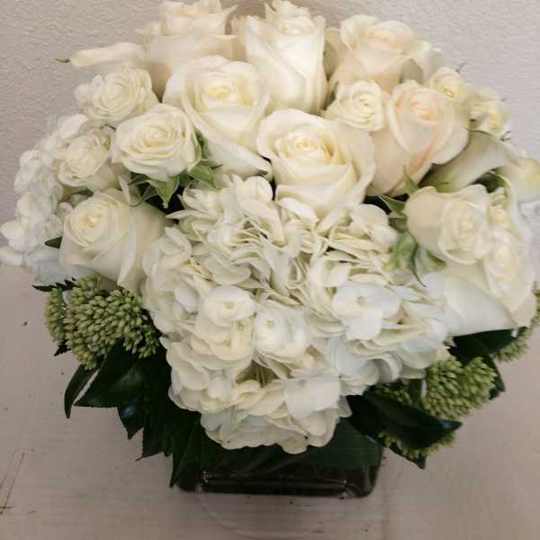 White roses and hydrangeas arranged in a low vase