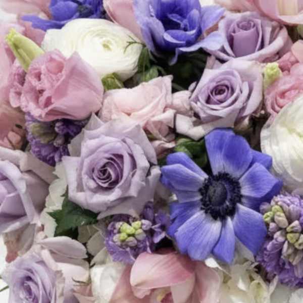 Bouquet of pastel roses, ranunculus, and purple anemones