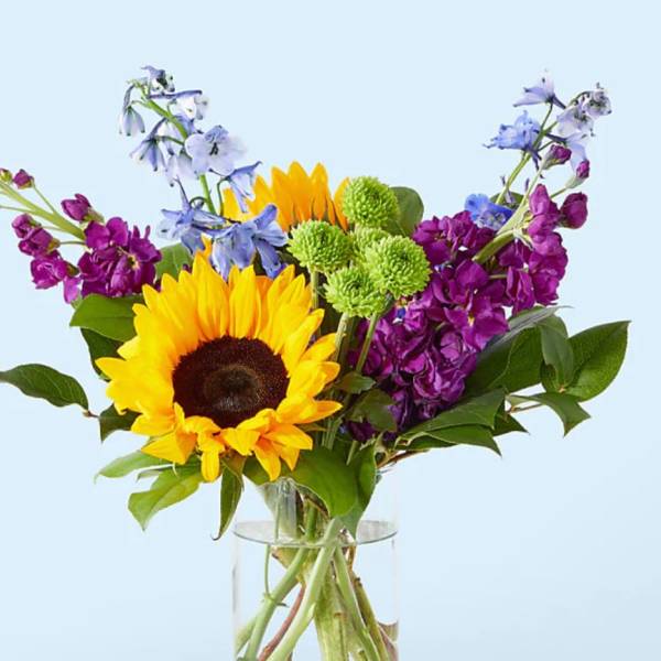 Sunflower bouquet with purple and blue flowers in a glass vase