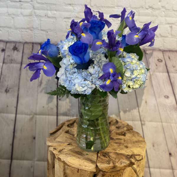 Blue roses and purple irises in a glass vase