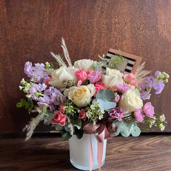 Mixed bouquet of pink, white, and lavender flowers in a white vase