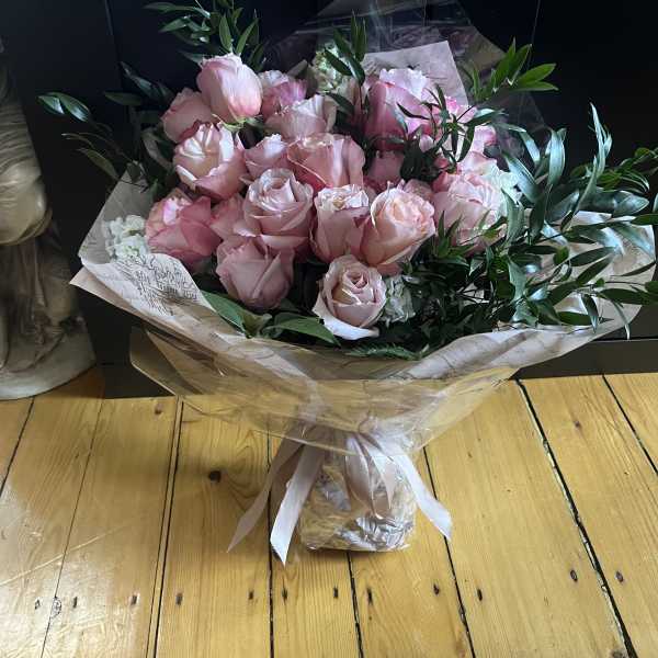 Bouquet of pale pink roses wrapped in paper with a ribbon