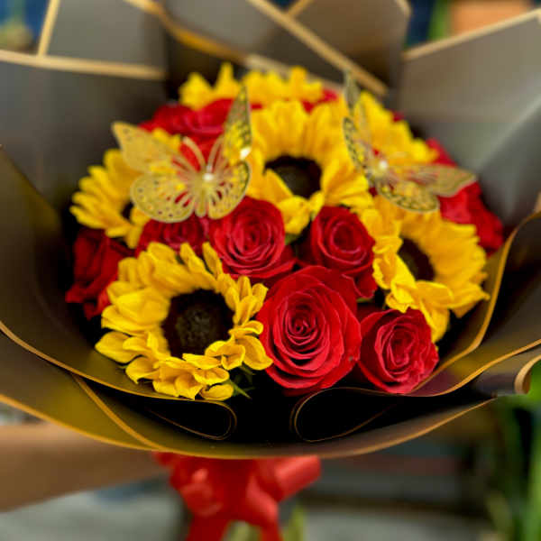 Bouquet of red roses and yellow sunflowers wrapped in dark paper