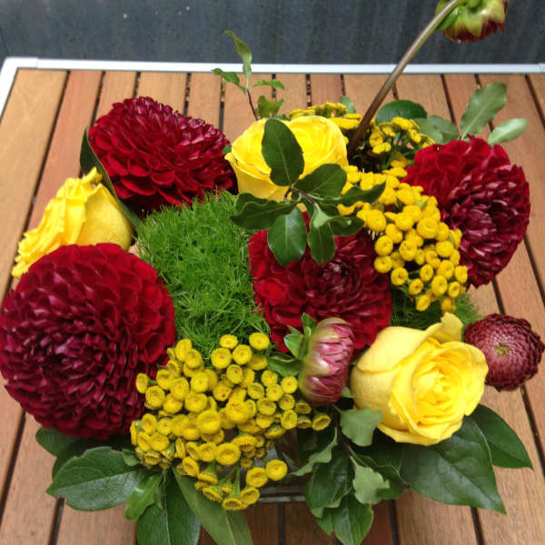 Low bouquet of red and yellow flowers in a container