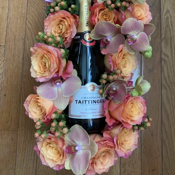 Champagne bottle surrounded by peach roses and orchids