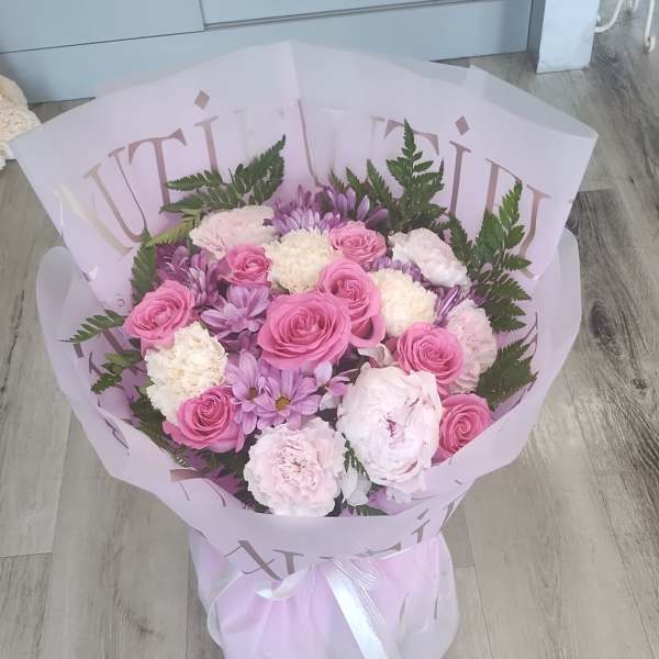 Pink and lavender bouquet with roses and carnations wrapped in pale paper