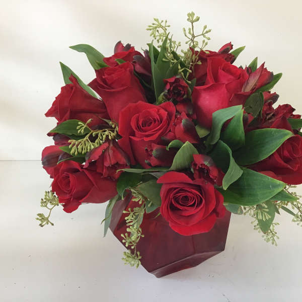 Red rose bouquet with green foliage in a burgundy wrap