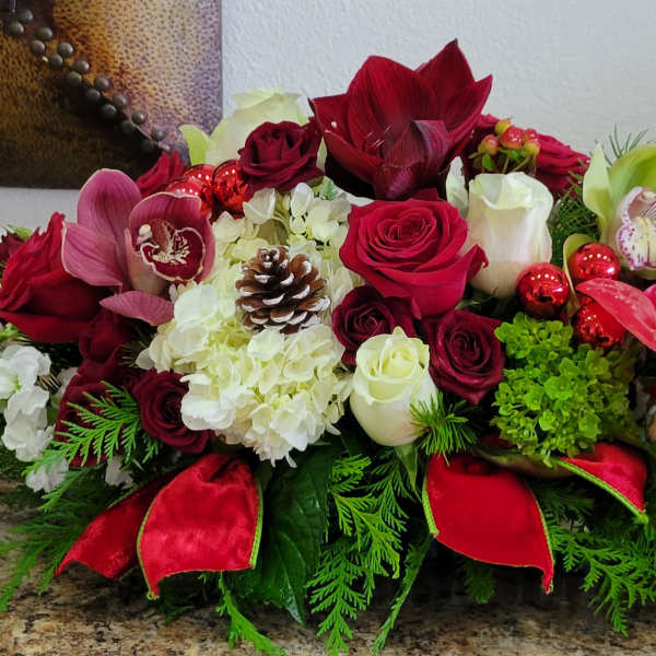 Red and white floral centerpiece with roses, orchids, and pinecones