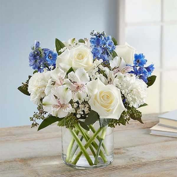 White and blue mixed bouquet in a clear glass vase