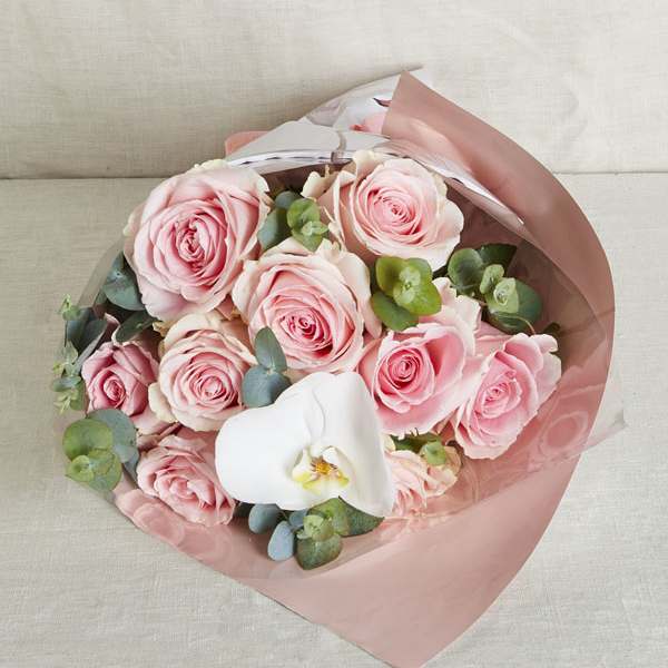 Bouquet of pink roses with a single white orchid wrapped in pink and clear paper